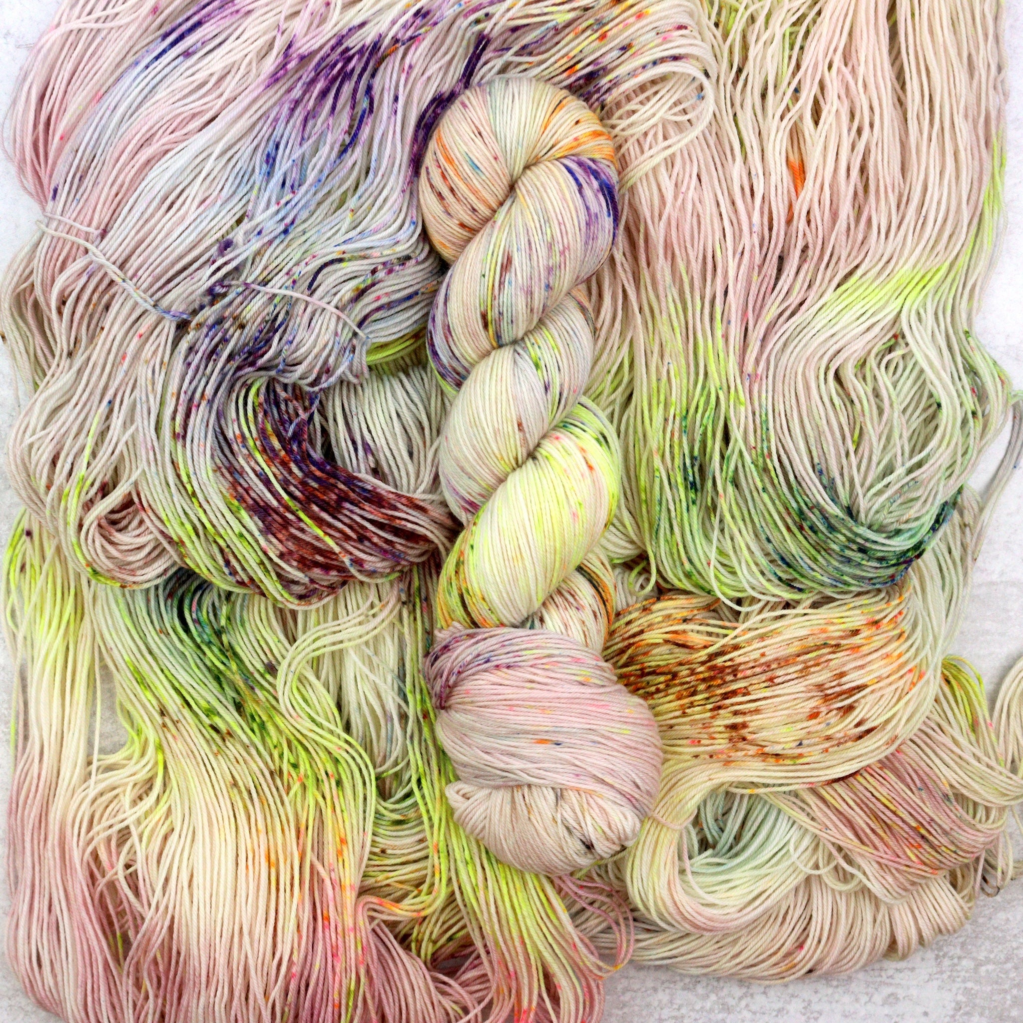Energize is hand dyed yarn featuring blue, purple, green, orange and brown on a soft pink base.