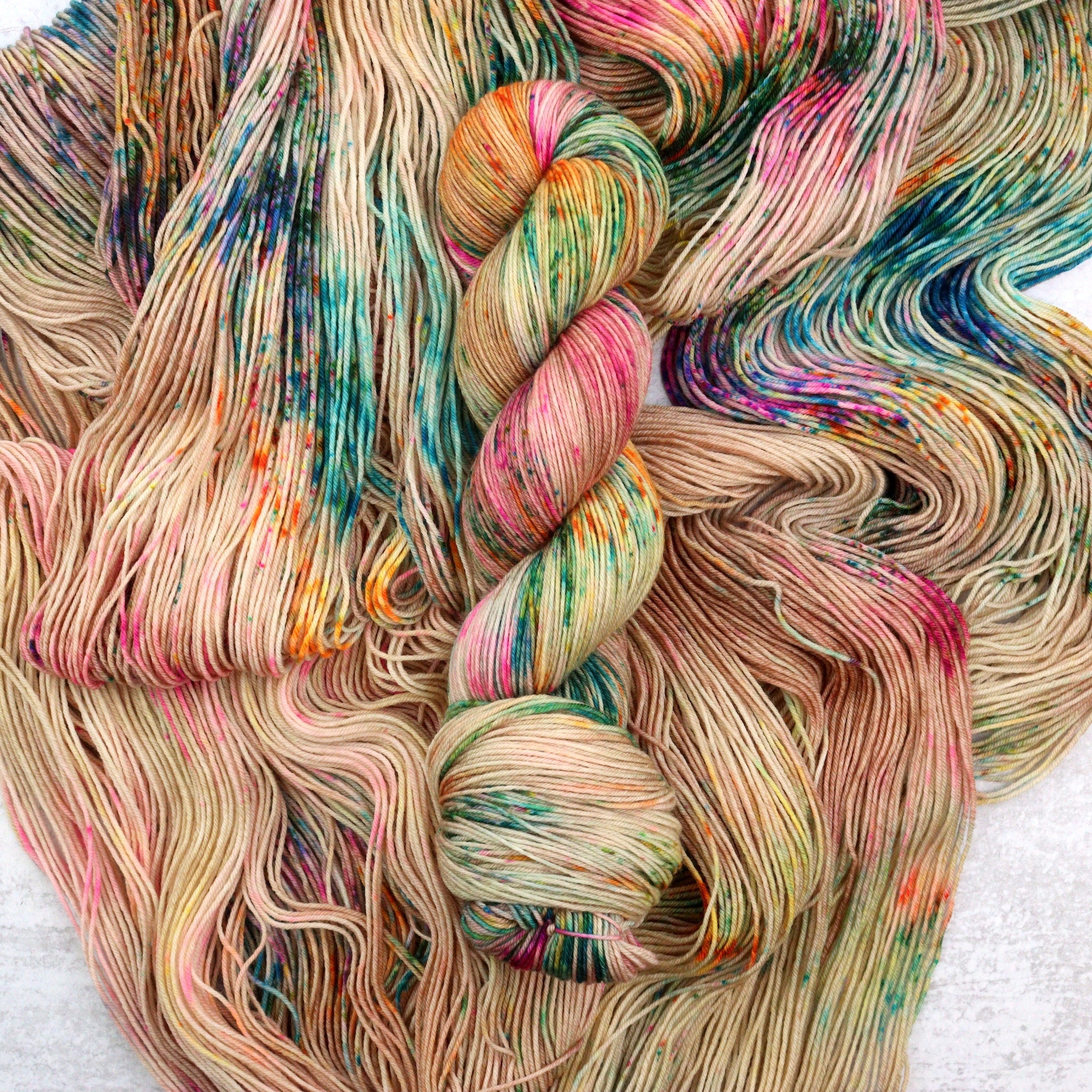 Hand dyed speckled yarn with pops of green, pink, purple, brown, turquoise and orange.