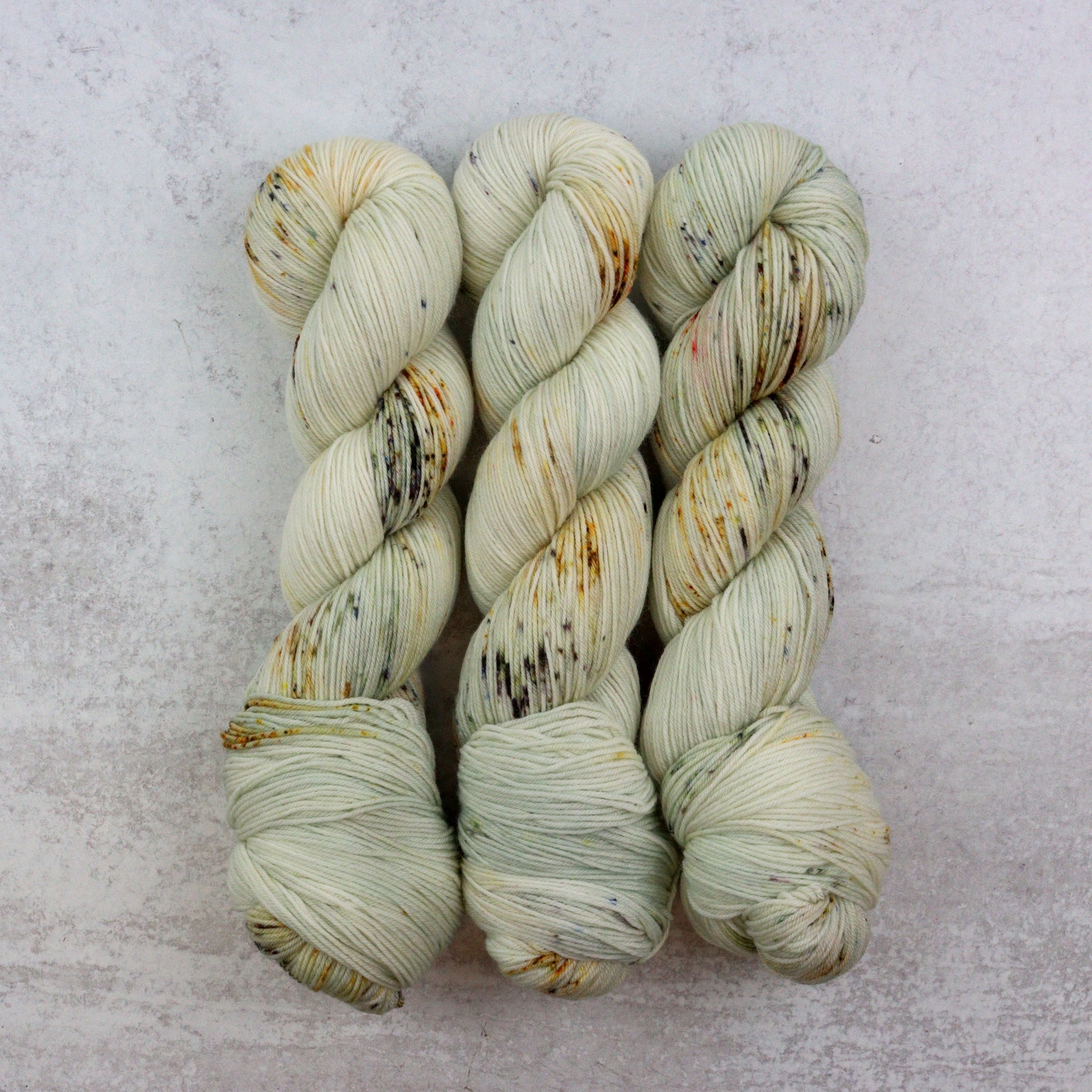 Hand dyed speckled skeins of superwash merino sock yarn.