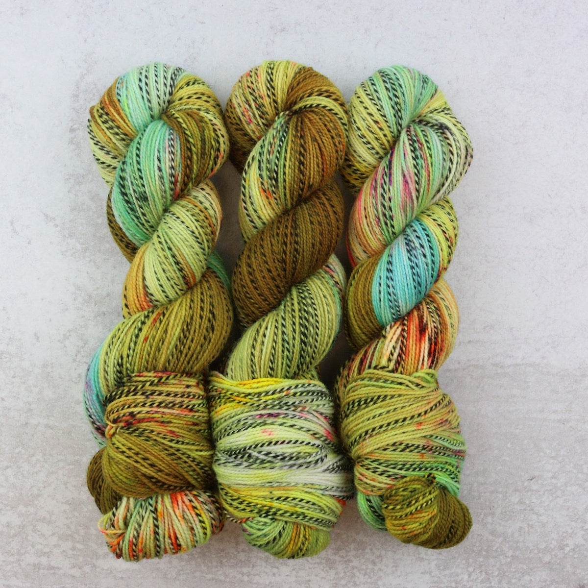 Green and yellow hand dyed yarn with aqua, orange and pink speckles.