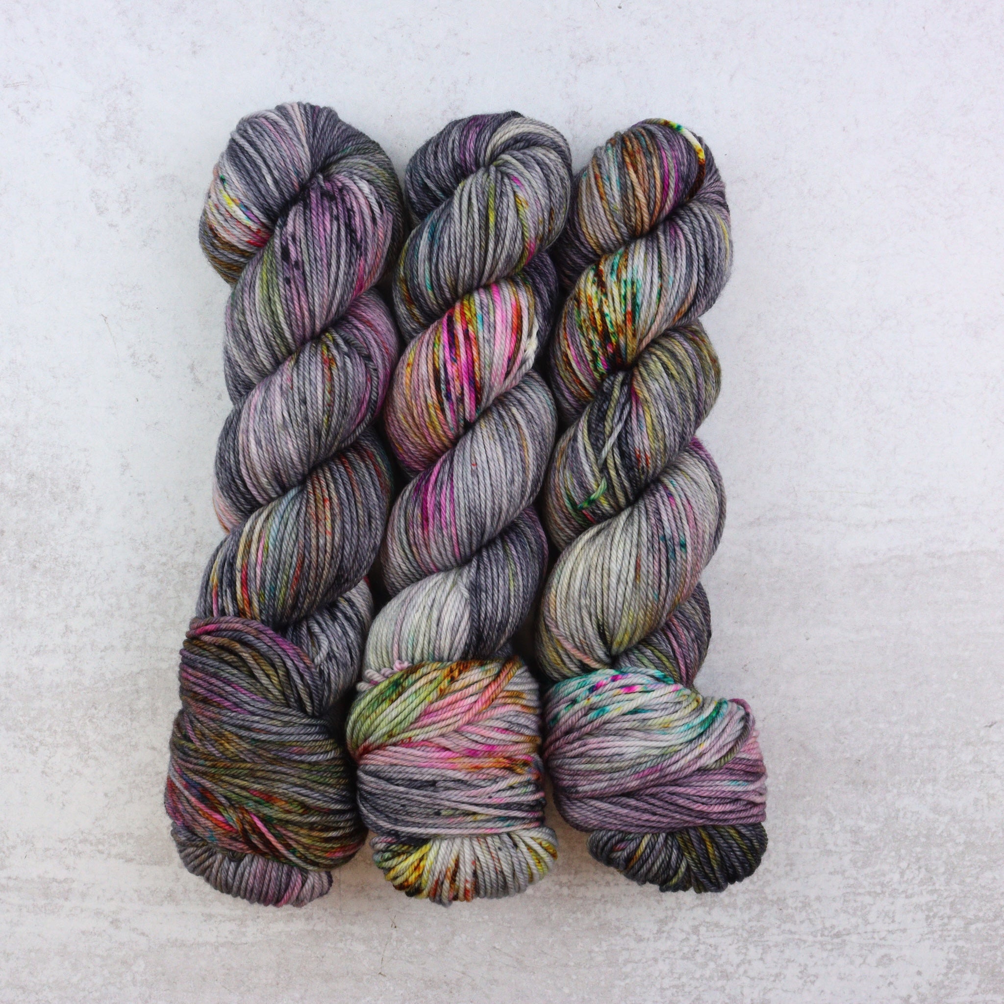 Hand dyed yarn with black, grey, brown, pink, orange and aqua speckles.