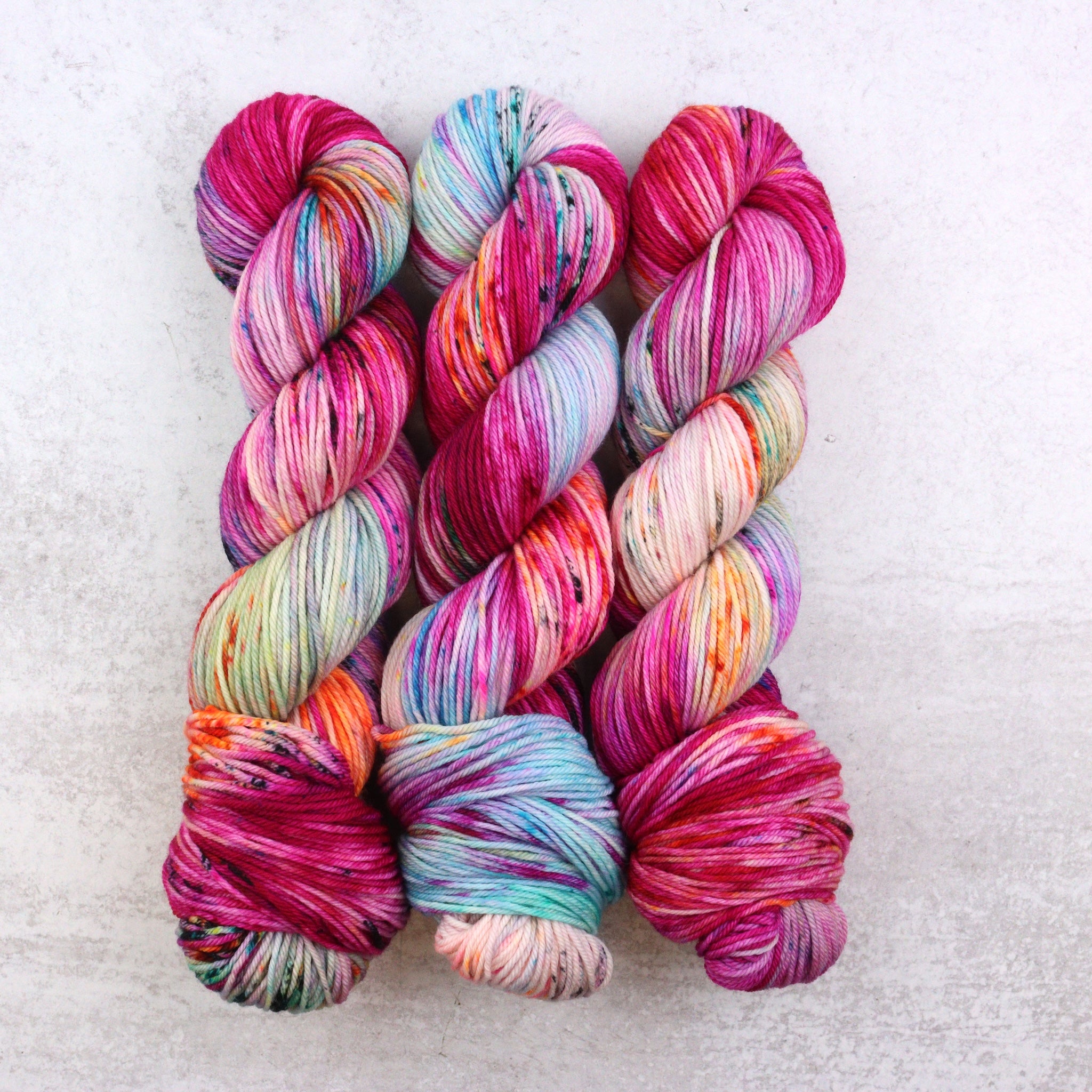 Multi colored skeins of hand dyed yarn featuring pink, aqua and orange.