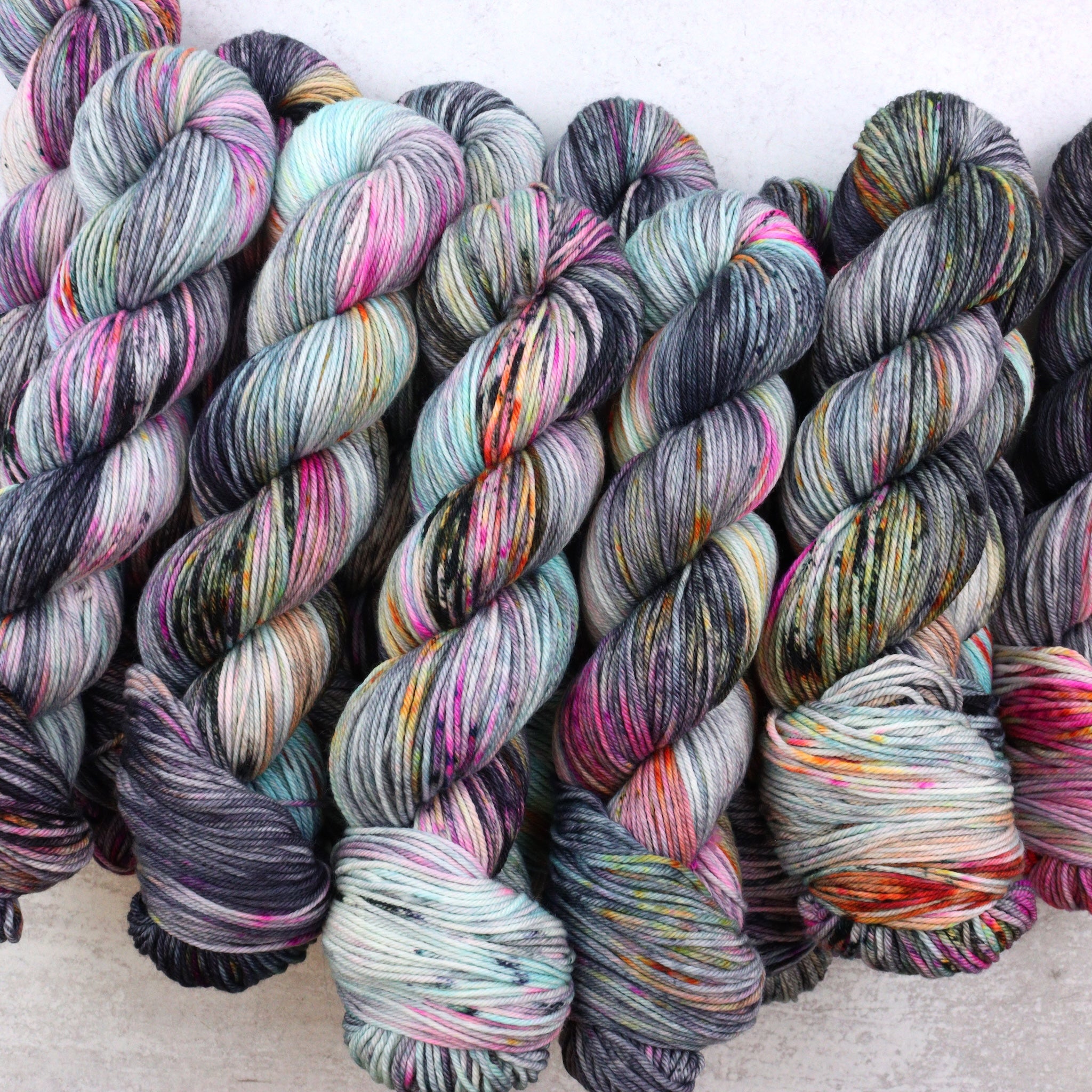 Hand dyed yarn featuring bright pops of hot pink, bright orange and aqua.