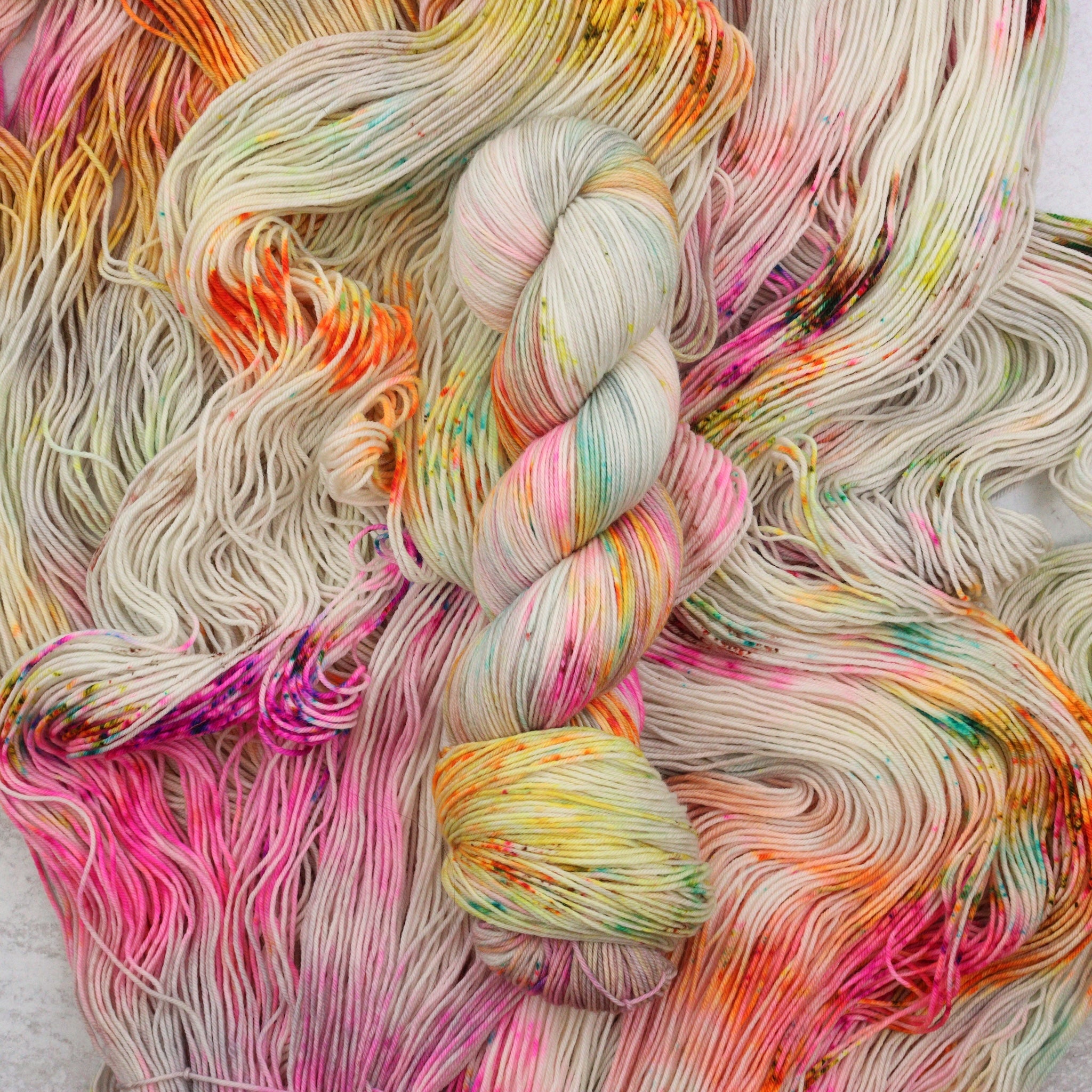 Hand dyed speckled yarn featuring pink, green, aqua, orange and brown.