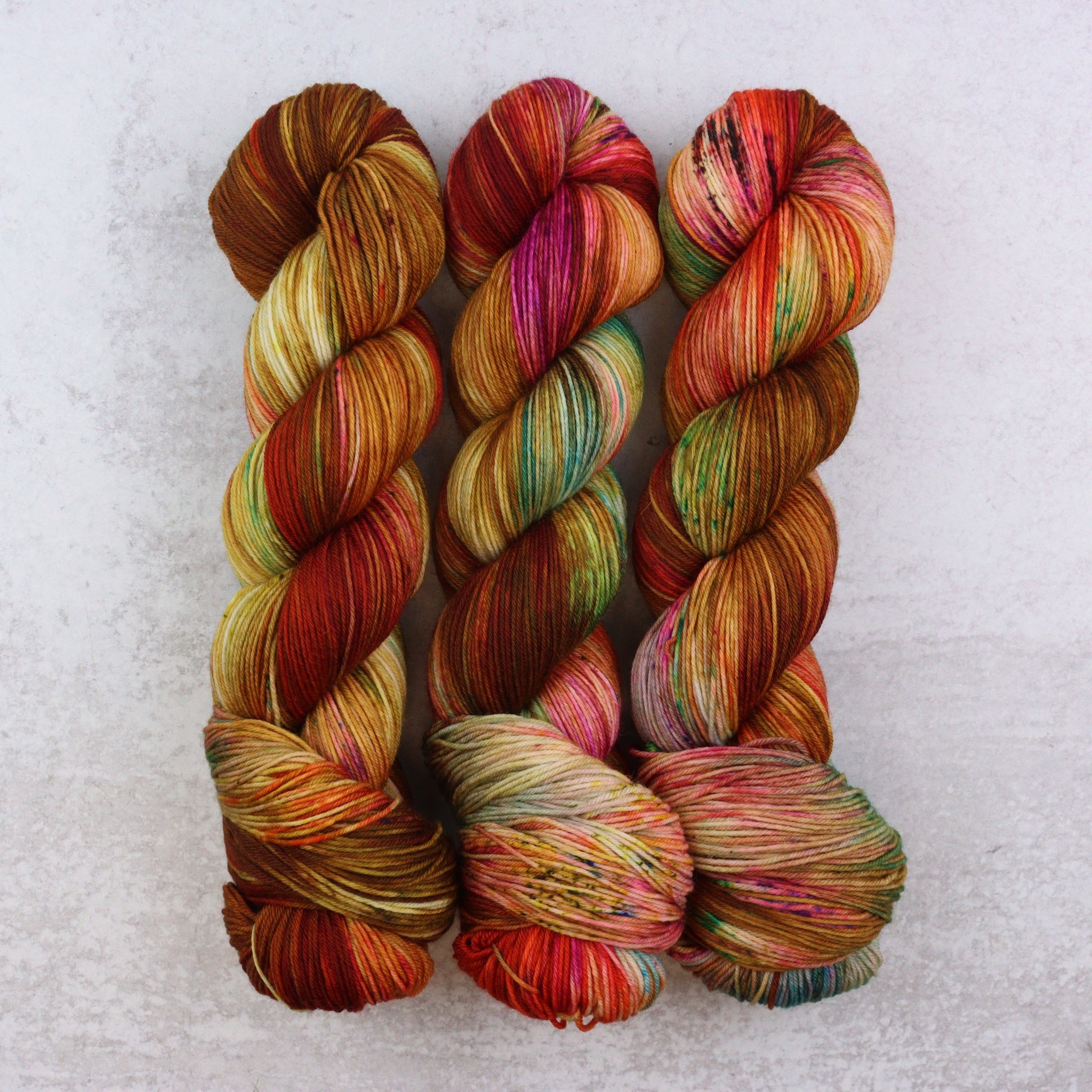 Three skeins of multicolored yarn on a textured white background