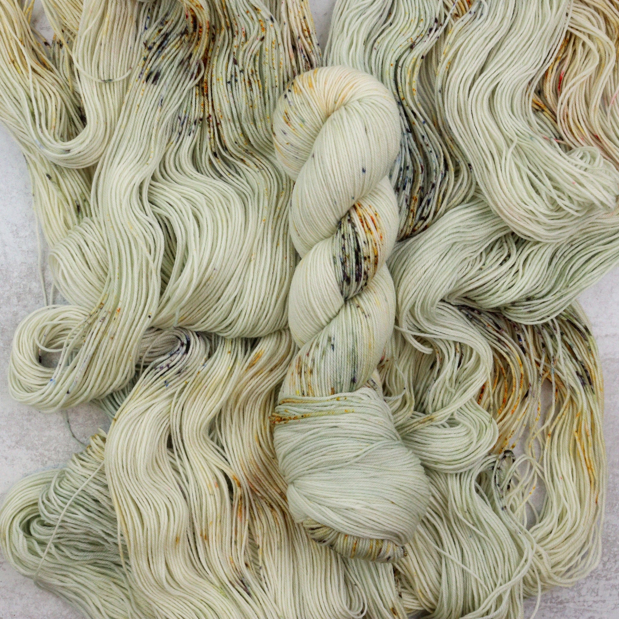 Hand dyed speckled skeins of superwash merino sock yarn.