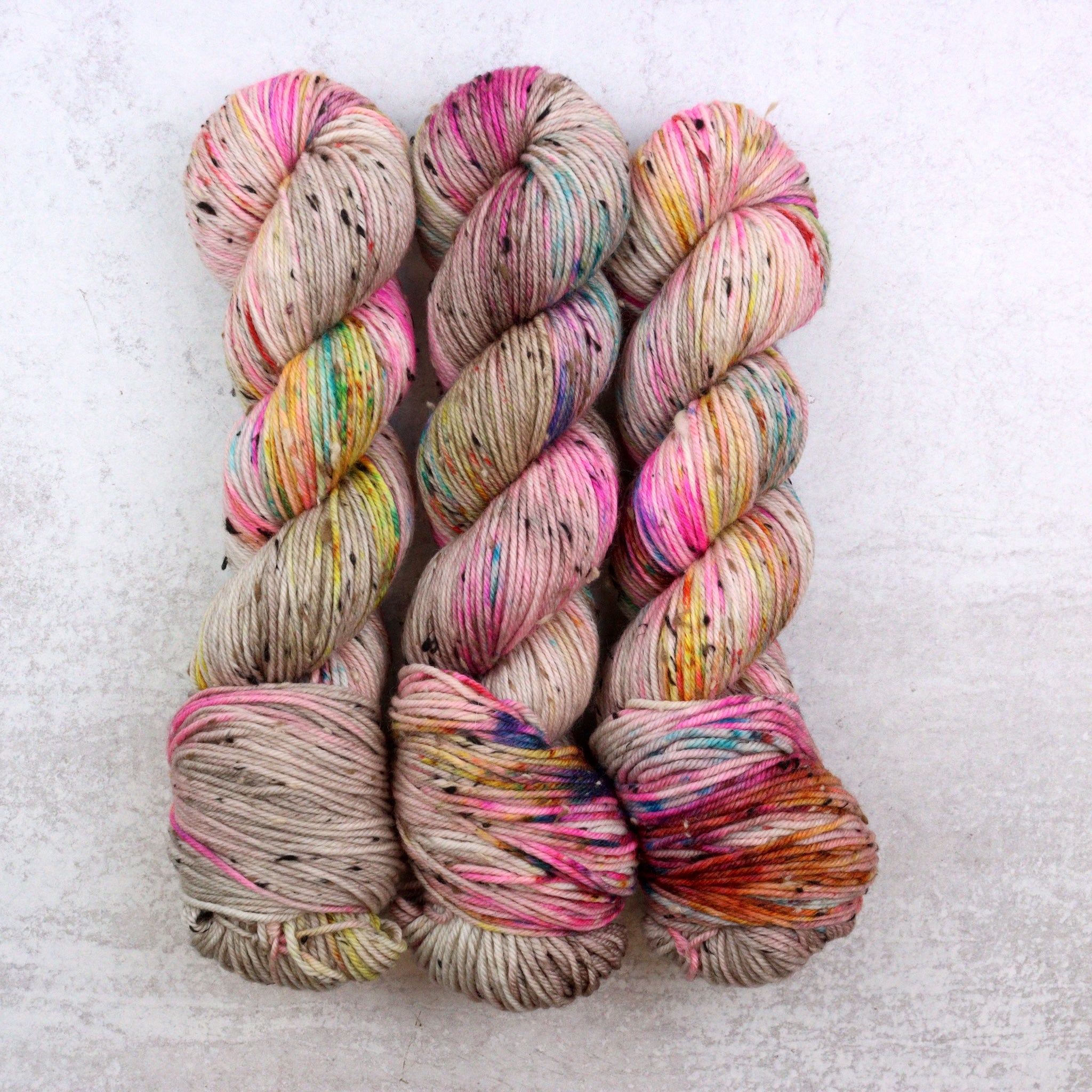 Three skeins of multicolored yarn on a light gray background