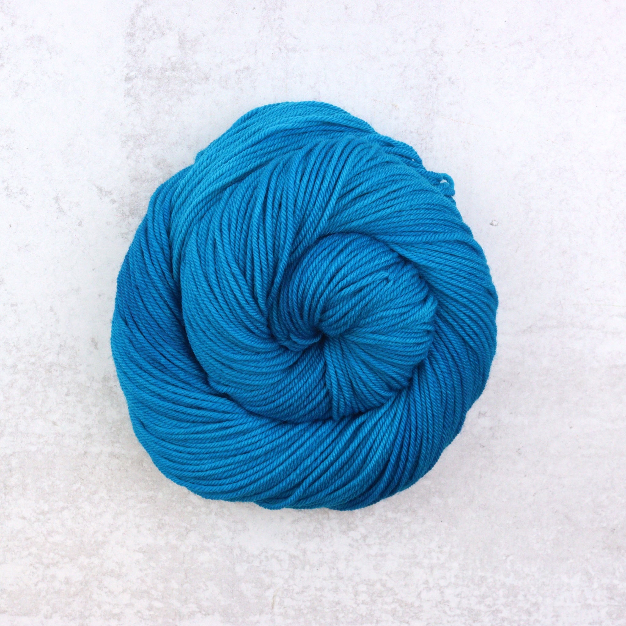 Hand dyed semi solid Dk weight yarn in a vibrant blue.