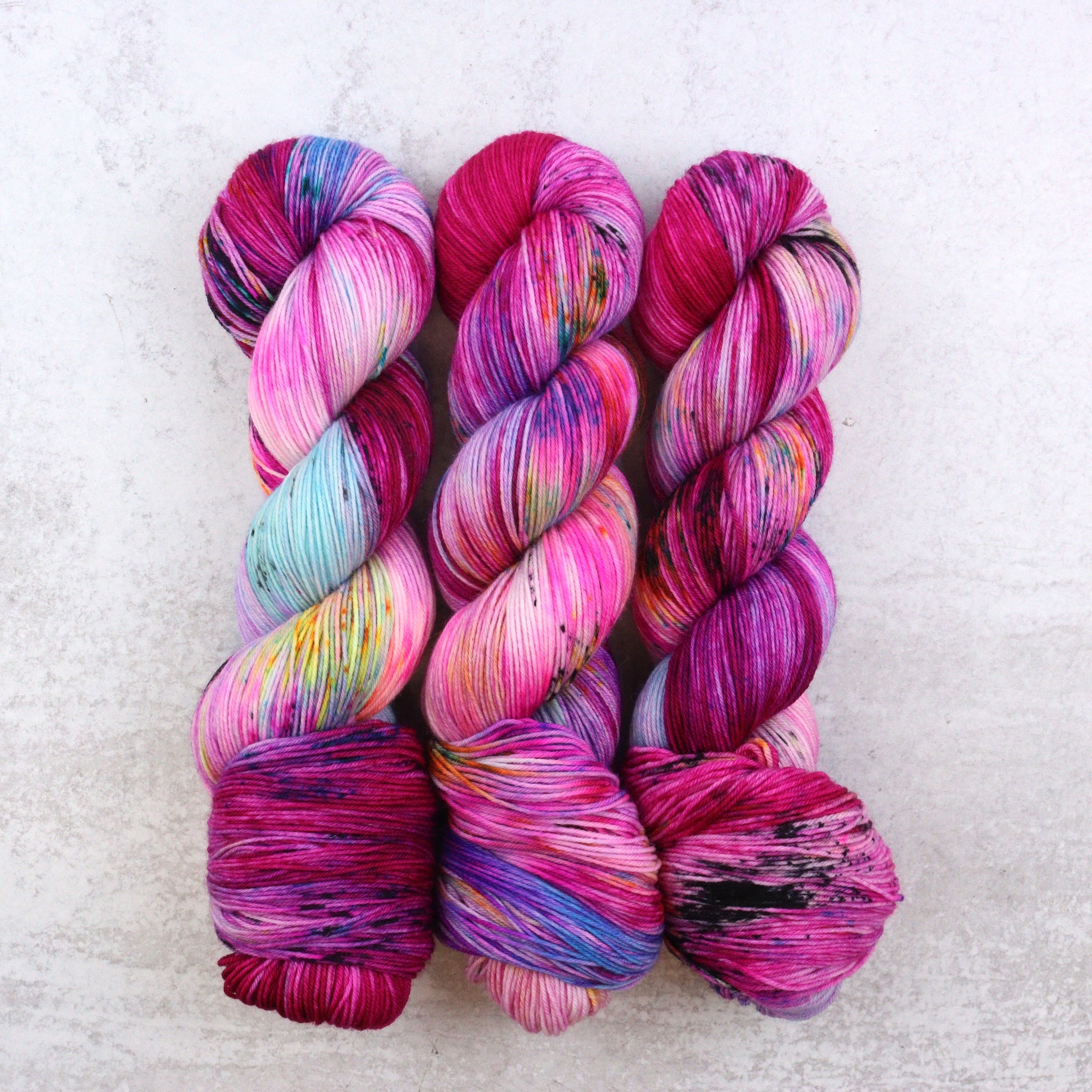 Multi colored skeins of hand dyed yarn featuring pink, aqua and orange.