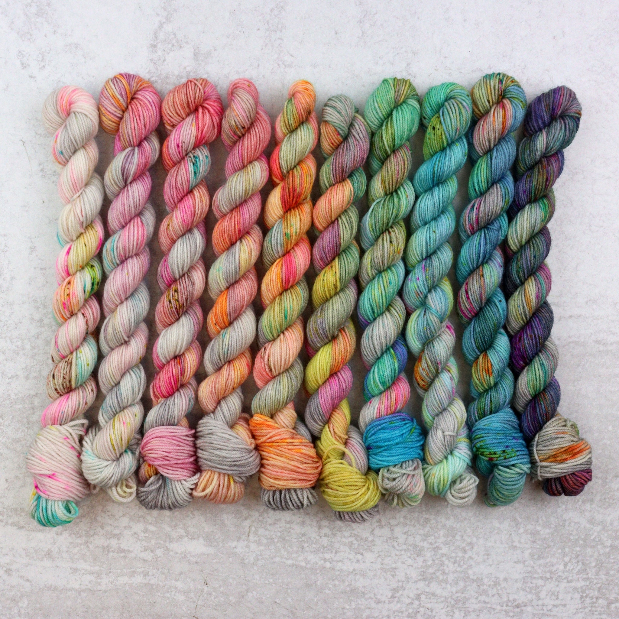 Mini skein collection hand dyed in grey, pink, orange, blue and green. 