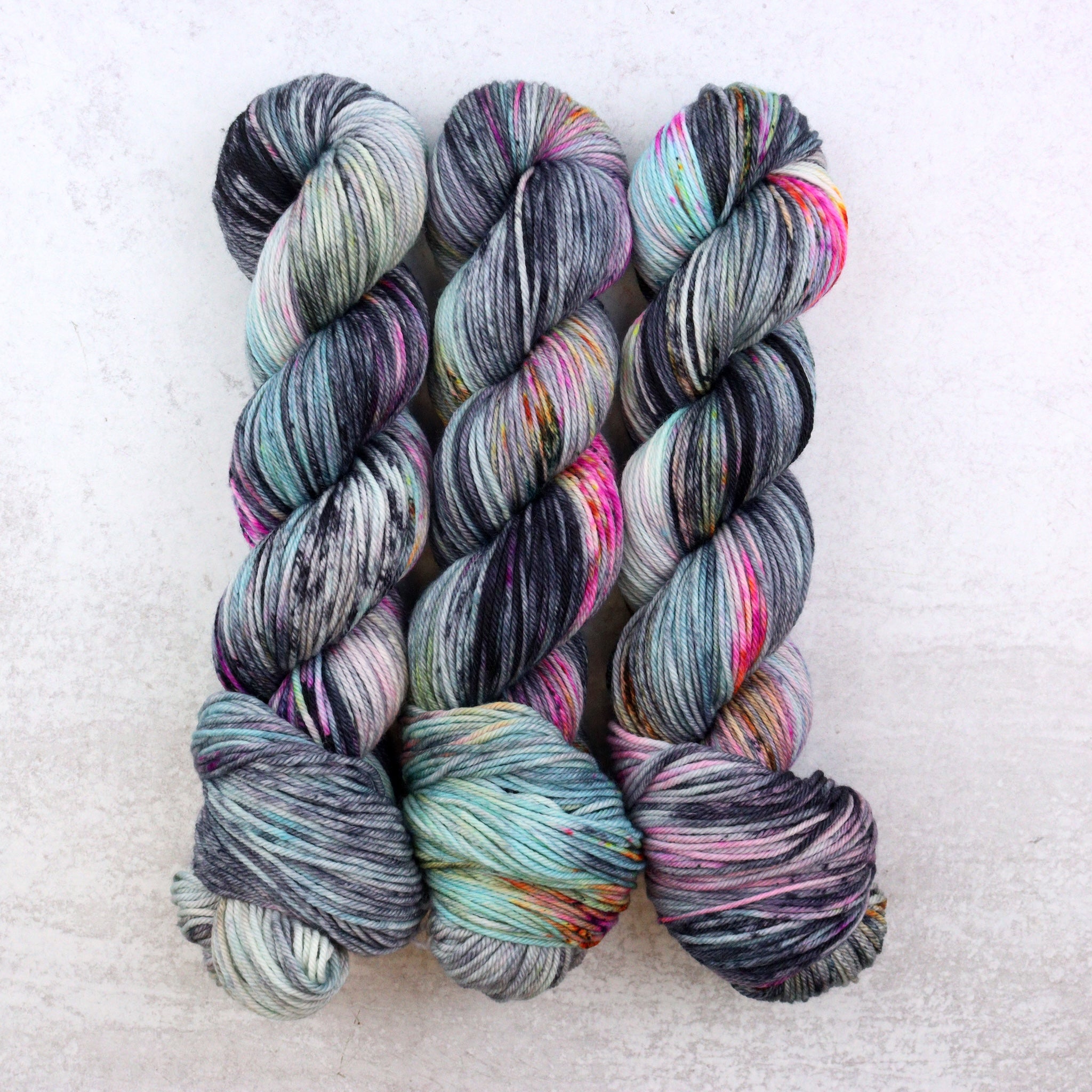 Hand dyed yarn featuring bright pops of hot pink, bright orange and aqua. 