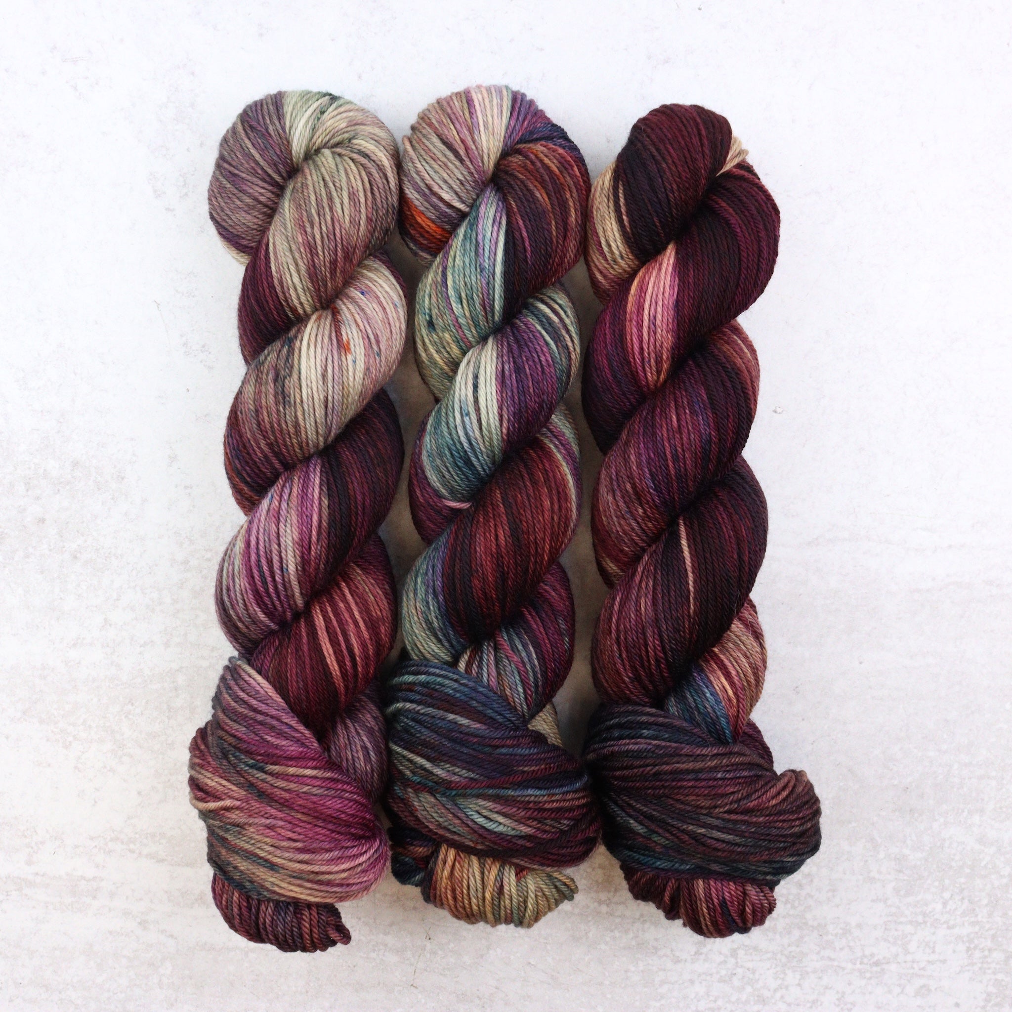 Variegated hand dyed DK weight yarn in brown, purple and teal by Spun Right Round.
