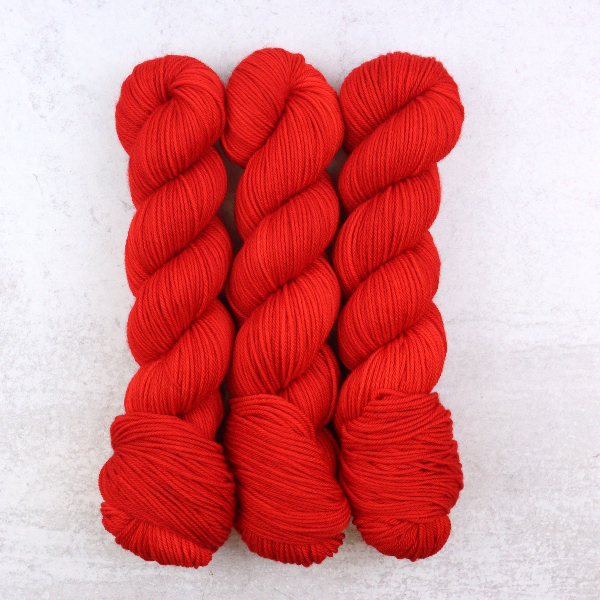 Hand dyed semi solid Dk weight yarn in a vibrant red.